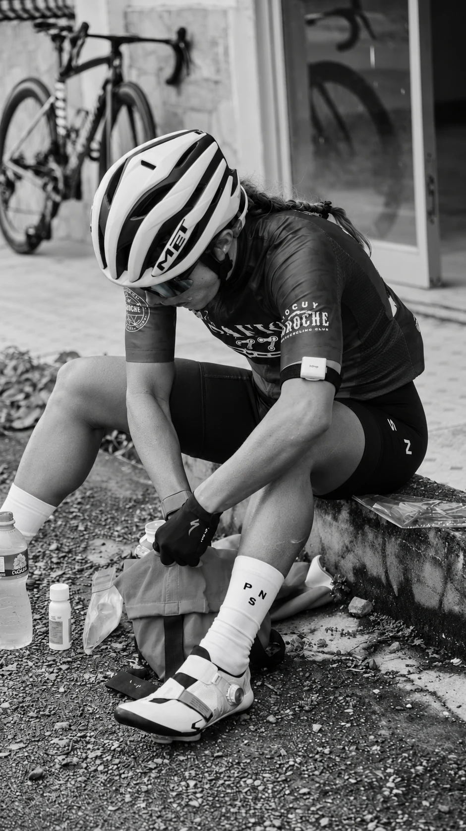 Cyclist seated beside a bike with an hDrop sweat sensor secured to her upper arm