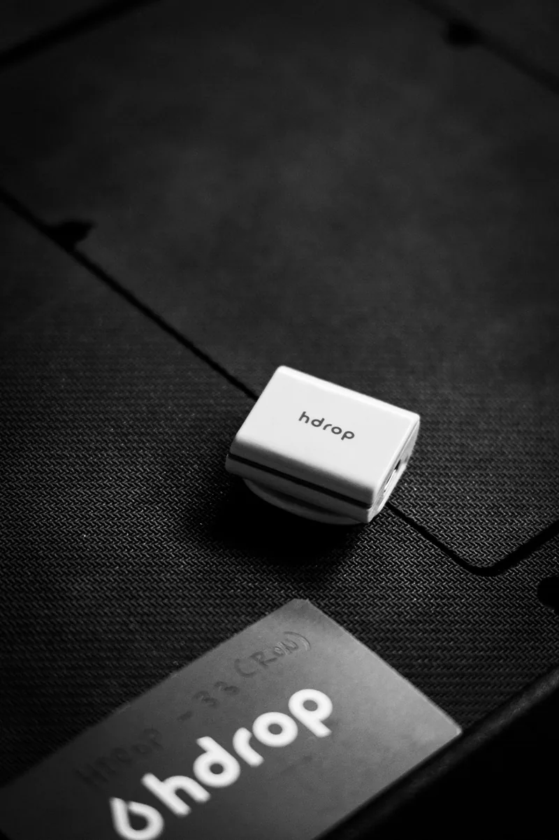 White hDrop sweat sensor resting on a black woven carrying case