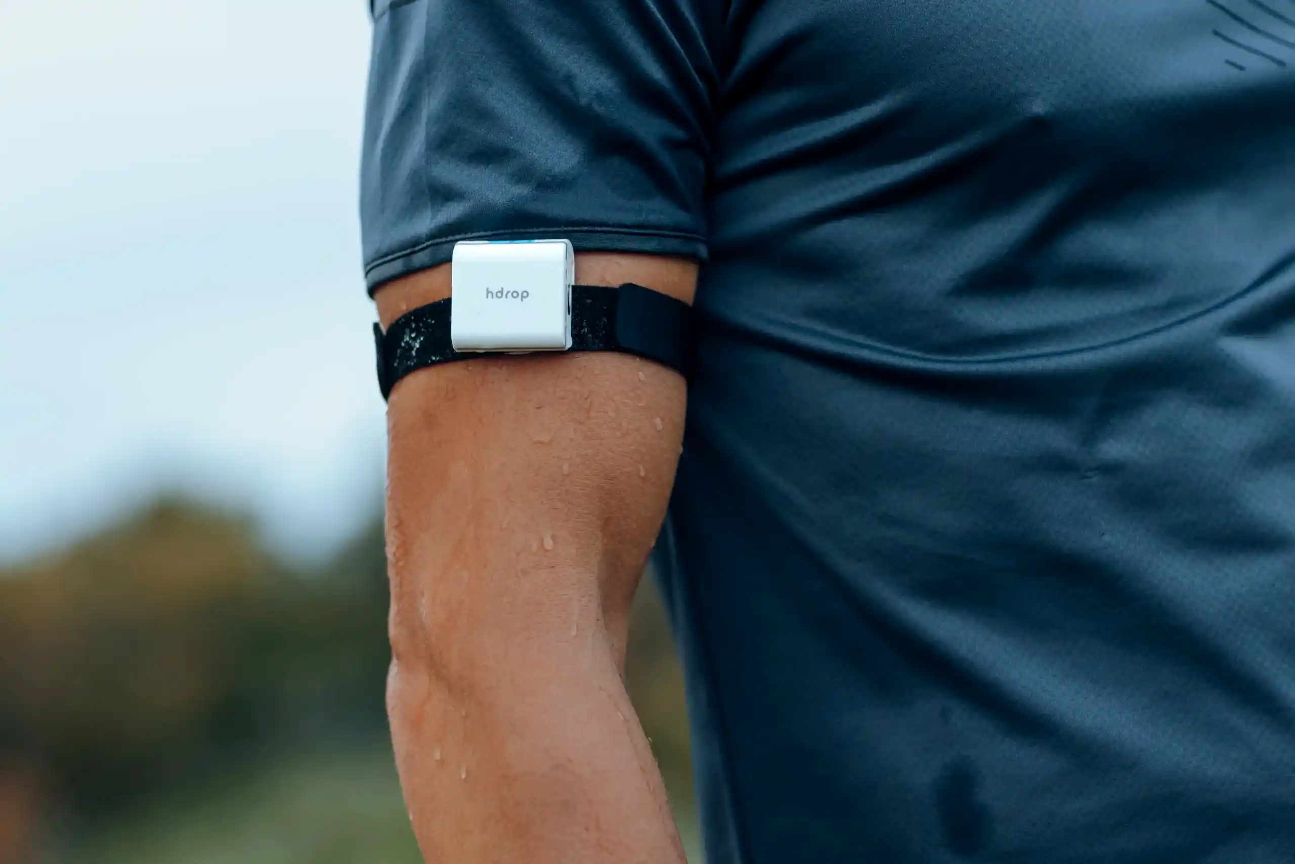 Close-up of an hDrop Gen 2 reusable sweat sensor worn on an athlete's upper arm